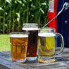 Close-up of three glasses of beer—cream ale, Kentucky common, and golden pre-prohibition lager—on a truck tailgate with a blurred cornfield background.