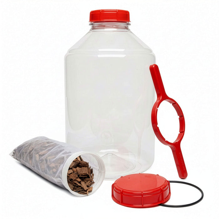Clear fermentor with mesh bag filled with oak chips, lid remover, black o-ring, red lid