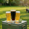 Three glasses of beer on a vintage cooler with a grassy background