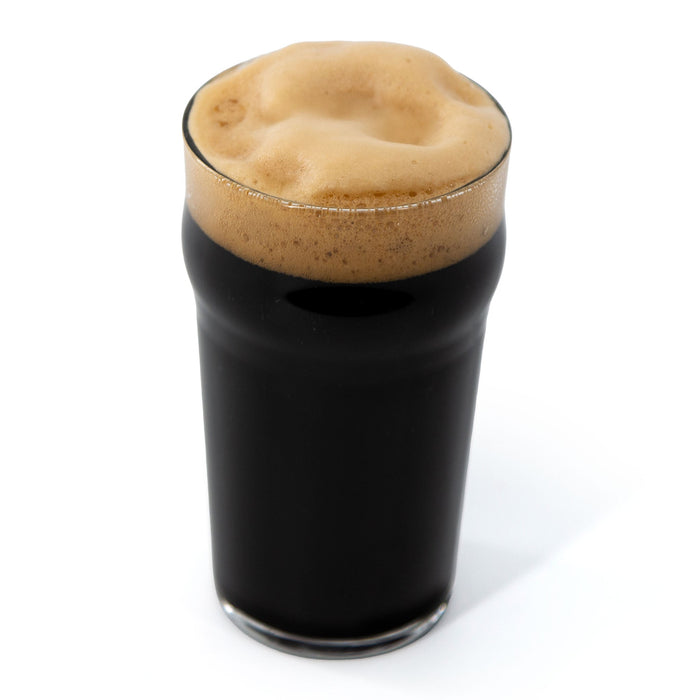 Dark beer with a thick head in a glass on a white background