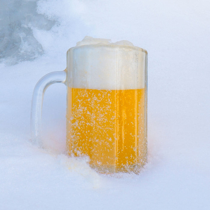 Permafrost India White Ale in a frosty mug sitting in a pile of snow