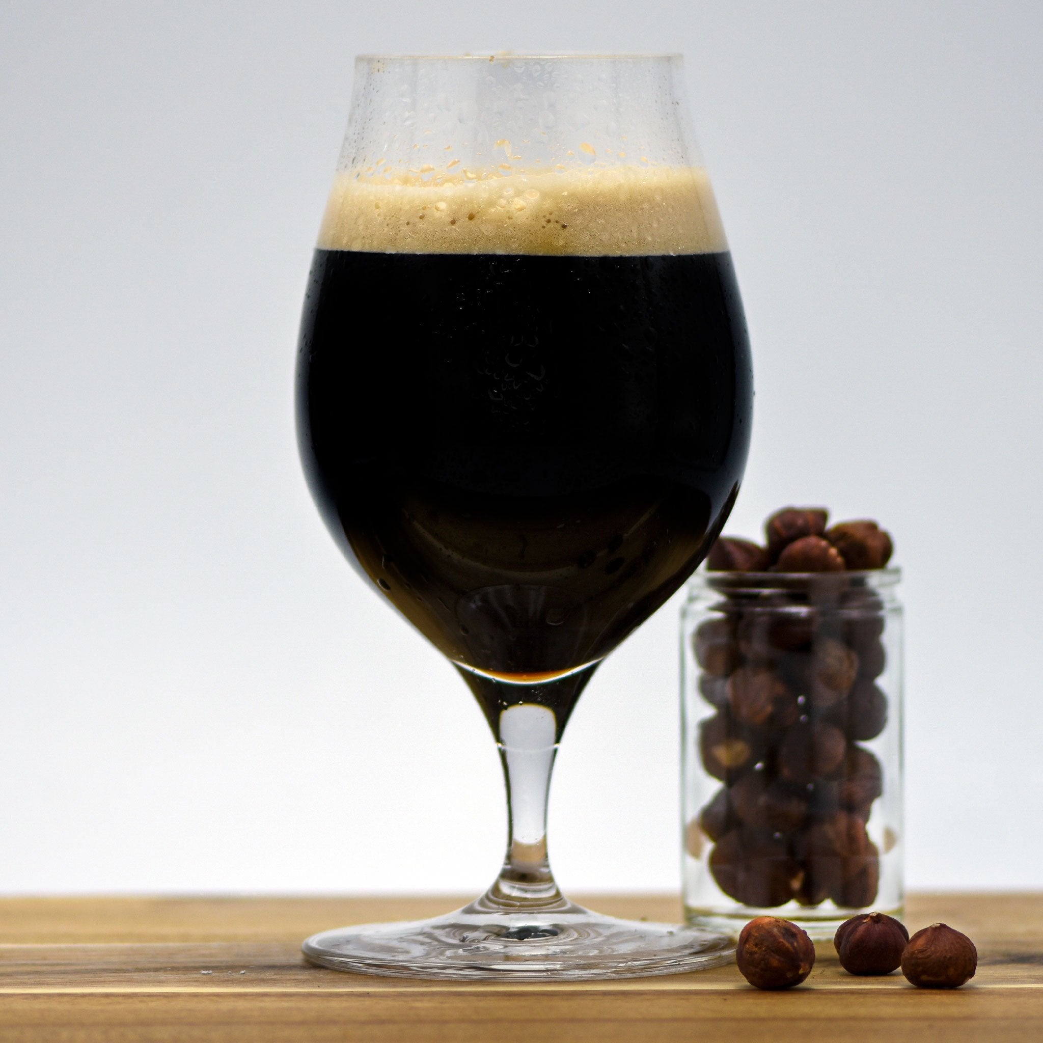 Hazelnut Pastry Stout with a glass filled with hazelnuts adjacent