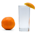 Navel Orange Hard Seltzer in a glass with an orange wedge next to a whole orange