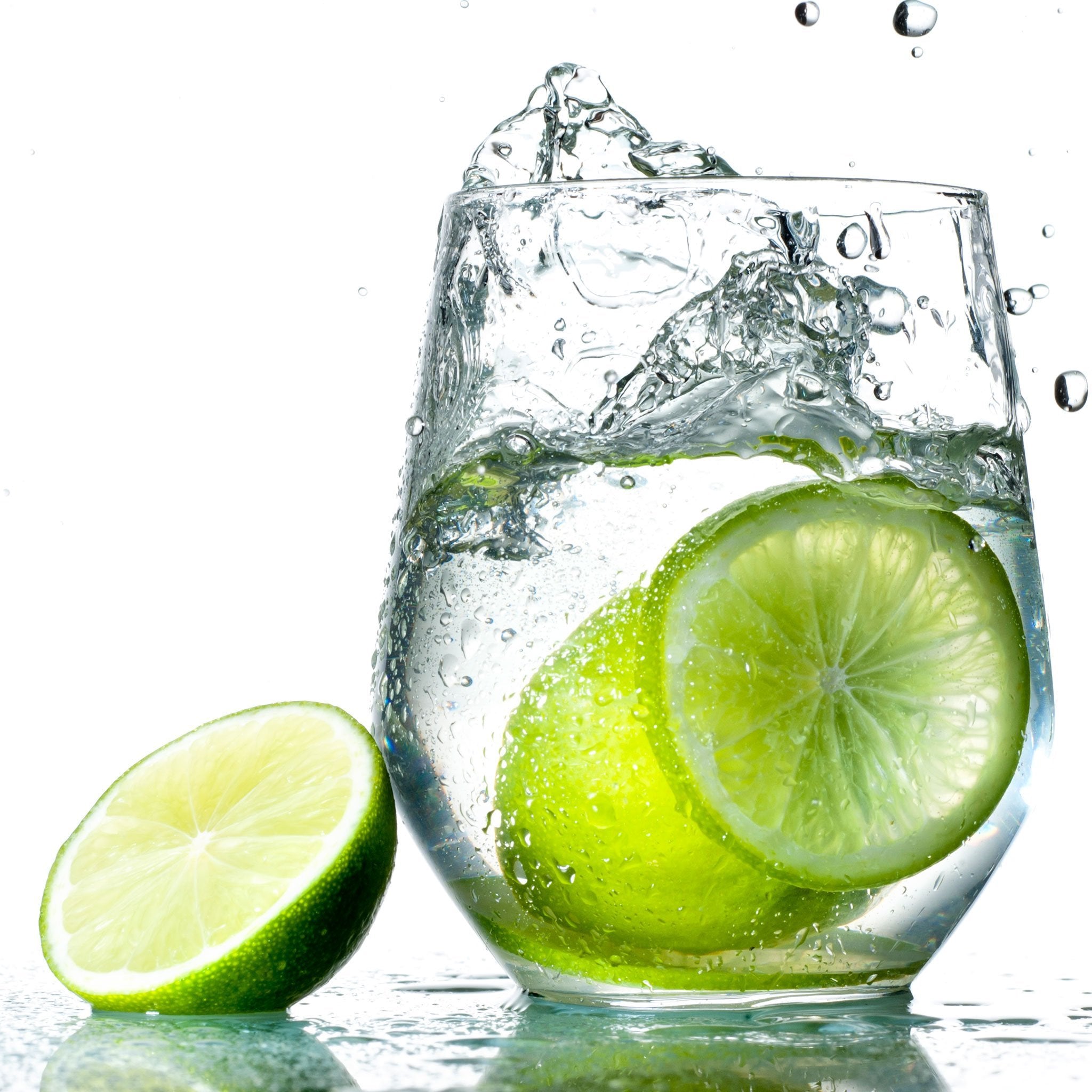A glass full of Lime Hard Seltzer with fresh limes next to the glass.
