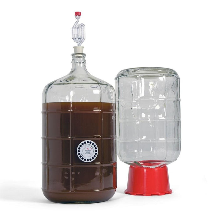 A filled carboy with adhesive thermometer and airlock, adjacent to a carboy in a carboy dryer
